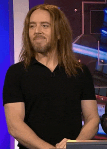 a man with long red hair and a beard wearing a black shirt