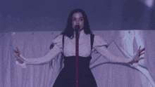 a woman is singing into a microphone with a purple background
