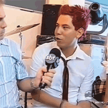a man with red hair is holding a microphone with the letters sbt on it
