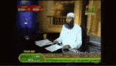 a man with a beard is sitting at a desk in front of a tv screen that says mtn on it