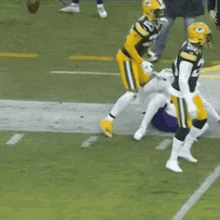 a group of football players are playing a game on a field with a referee .