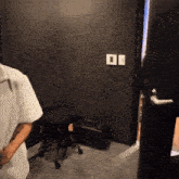 a person is standing in a room with a black door and a white square on the wall