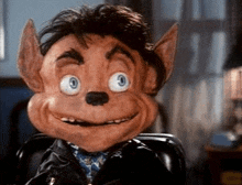 a close up of a puppet with a big smile on his face sitting in a chair .