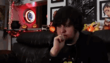 a man with a beard is sitting on a couch with his hand in his mouth