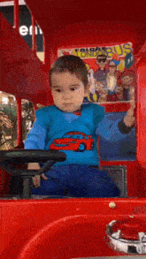 a little boy is sitting in a toy bus with a poster on the side that says sonic the hedgehog