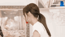 a woman wearing a ponytail with a cherry in her ear and a vlive logo behind her