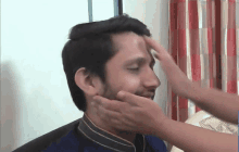 a man 's face is touched by a woman 's hand