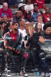 a man in a video game costume sits in the stands at a basketball game with a viggle.ai watermark