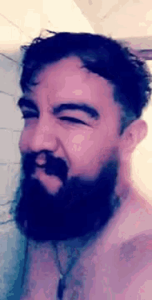 a man with a beard is taking a shower and making a funny face