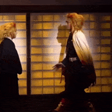 a man in a costume is standing next to another man in a costume in front of a window .