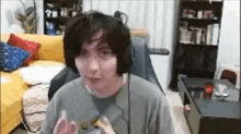 a young man wearing headphones is sitting in a living room with a yellow couch .