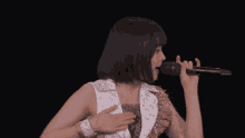 a young woman is singing into a microphone on a stage in a dark room .