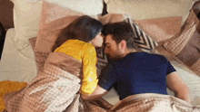 a man and a woman are kissing while laying in bed .