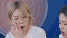 a woman wearing glasses and a white shirt eating something