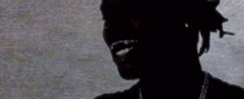 a silhouette of a man with dreadlocks and a necklace on his neck .