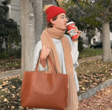 a person wearing a red hat and scarf is holding a starbucks cup