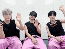 three young men wearing pink pants and sunglasses are sitting in chairs