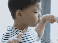 a young boy in a striped shirt is eating something with a fork .
