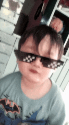a young boy wearing sunglasses and a shirt that says batman