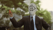 a man in a suit and tie with a mask on his face is holding a tomato .