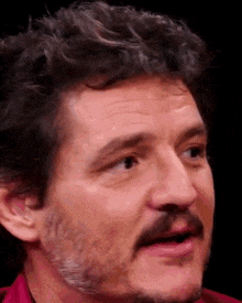 a close up of a man with a beard and curly hair making a funny face .