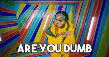 a man with a tattoo on his face is dancing in front of a colorful background and the words `` are you dumb '' .