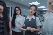 a group of girls are standing in a room and one of them is wearing glasses