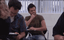 a man in a 68 shirt is sitting in a classroom with other students .