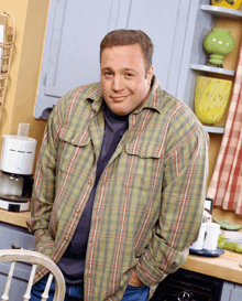 a man in a plaid shirt is standing in a kitchen