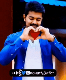 a man in a blue shirt making a heart with his hands