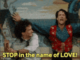 two men are standing in front of a painting with the words " stop in the name of love " on the bottom