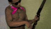 a shirtless man wearing sunglasses and a pink bandana is holding a shotgun ..