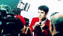 a man in a red suit is being photographed by a camera