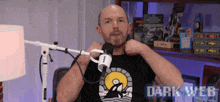 a man sitting in front of a microphone wearing a black shirt that says dark web