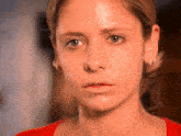 a close up of a woman 's face with a red shirt and earrings