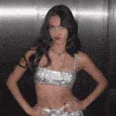 a woman wearing a crop top with rhinestones and a necklace is standing with her hands on her hips