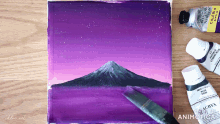 a painting of a mountain with a brush and bottles of acrya