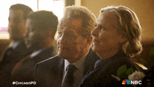 a man and a woman are sitting next to each other with a nbc logo in the background