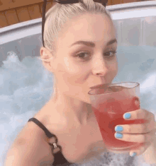 a woman in a hot tub drinking a red drink