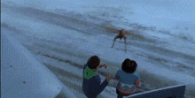 a couple of people standing on top of a staircase looking at a spider flying over the ocean .