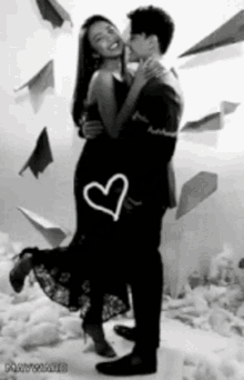 a black and white photo of a man holding a woman with a heart drawn on it