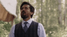 a man in a suit and tie is standing in a forest .
