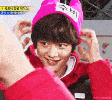 a young man wearing a pink hat with chinese writing