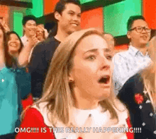 a woman is sitting in front of a crowd of people with her mouth open and a surprised look on her face .