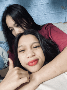 two girls are posing for a picture and one is giving the thumbs up