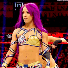 a woman with purple hair is standing in a wrestling ring with a man behind her .