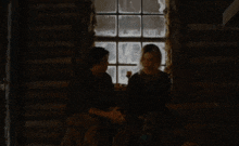 a man and a woman are sitting in front of a window
