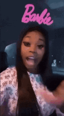 a woman is sitting in a car with a barbie logo in the back