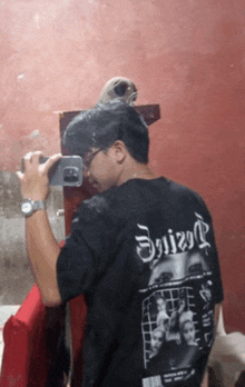 a man is taking a picture of himself in a mirror wearing a shirt that says ' sniper ' on it