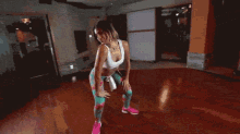 a woman in a white tank top and floral leggings is dancing